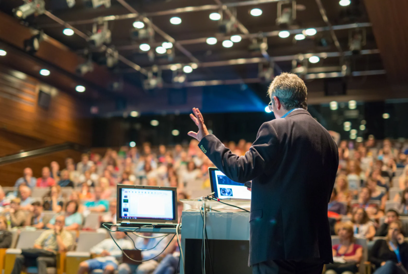 ein Mann steht vor einem Publikum und referiert